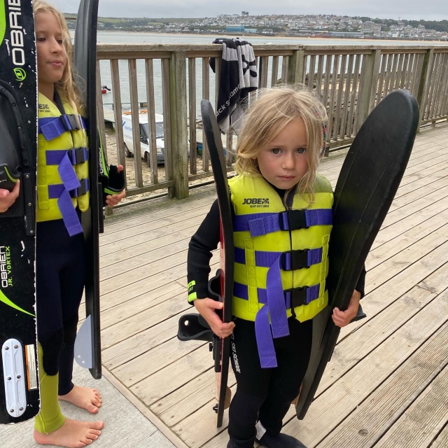 Chicas con chalecos salvavidas amarillos preparándose para el esquí acuático