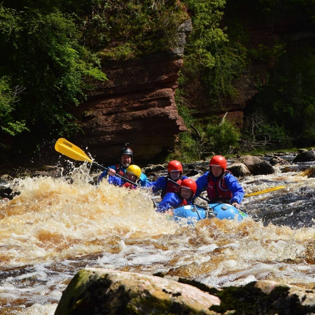  personas con trajes azules y rafting en el río Findhorn