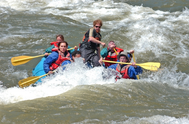  Personas con cascos rojos duranle su carrera de rafting 