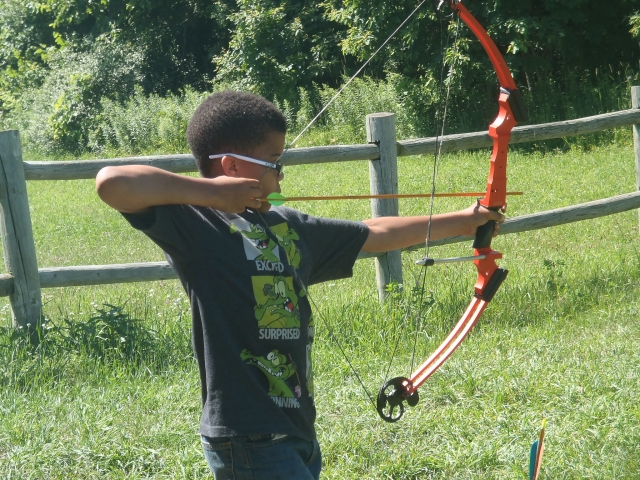  Niño con lentes de sol haciendo jalo con arco 