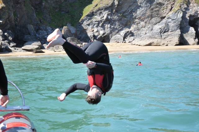  Niño con chalecos rojos y neopreno negro saltando desde un acantilado 