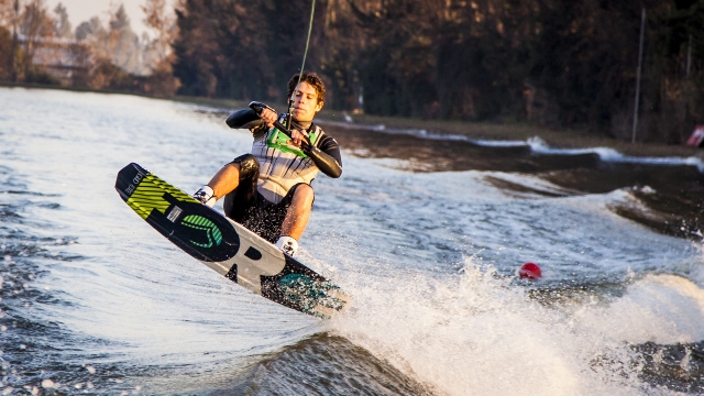  Niño con traje de neopreno verde y negro practicando wakeboard 