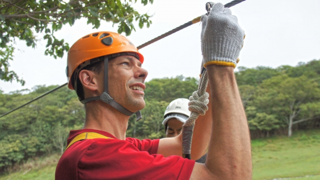 Hombre con casco naranja y guantes blancos a punto de disfrutar de la tirolesa