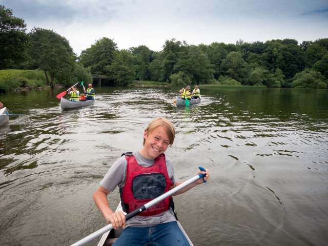  Un chavo vistiendo rojo ayudas a la flotabilidad mientras navega en canoa 