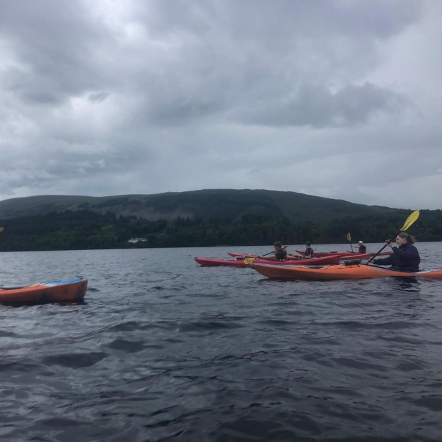  Personas navegando en canoa por el lago y la cerro al fondo 