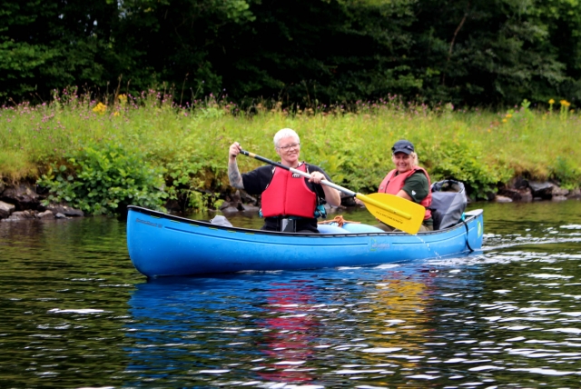  Dos mujes con ayudas a la flotabilidad rojas sonriendo y felices duranle el viaje en canoa 