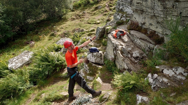  Hombre con casco rojo y playera naranja a punto de escalar 