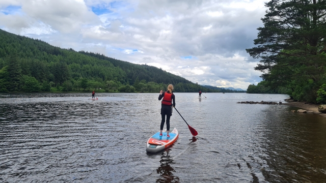  Tres personas con ayudas a la flotabilidad rojas haciendo paddleboarding 