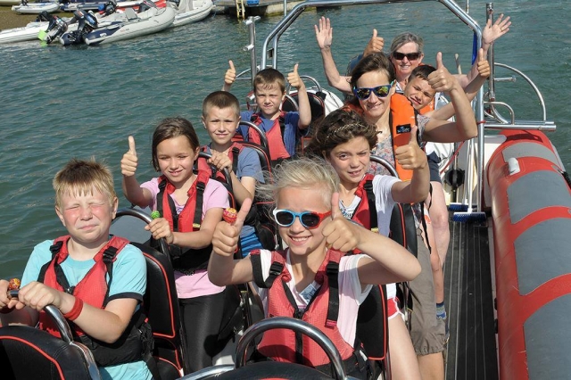  Niños con chalecos de ayuda a la flotabilidad rojos divirtiéndose duranle su viaje en barco 