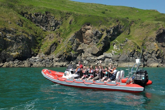  Personas con chalecos naranjas y ayudas a la flotabilidad rojas duranle su viaje en barco