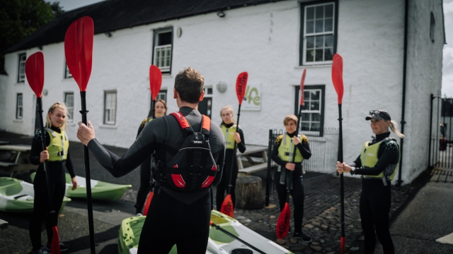  Grupo con chalecos de flotación verdes preparándose para navegar en kayak 
