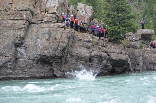  Gran grupo de personas vestidas de rojo ayudas a la flotabilidad para nadar y saltar duranle su aventura en coasteering