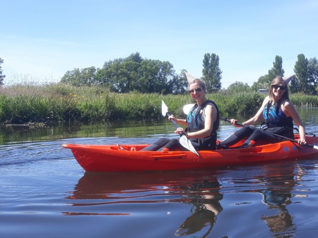  Dos niñas sonriendo y con lentes de sol navegando en kayak en el puerto 