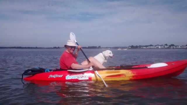  Hombre sonriendo, con lentes de sol y navegando en kayak con su perro 