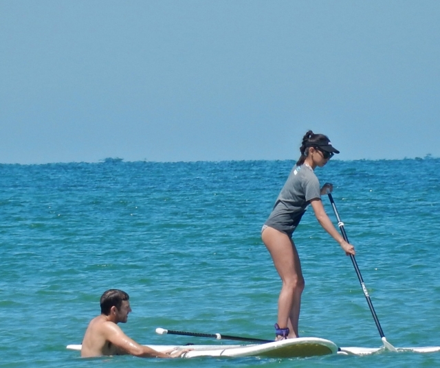  Chica con playera y gorra azul siendo ayudada por su instructor duranle su experiencia de paddleboarding 