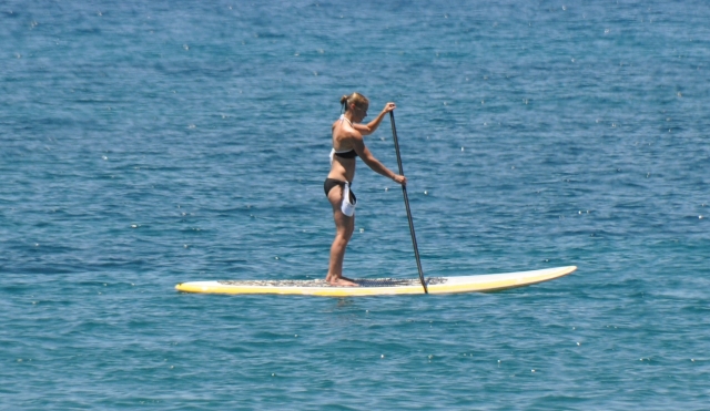  Mujer en bikini negro y azul haciendo paddleboarding 