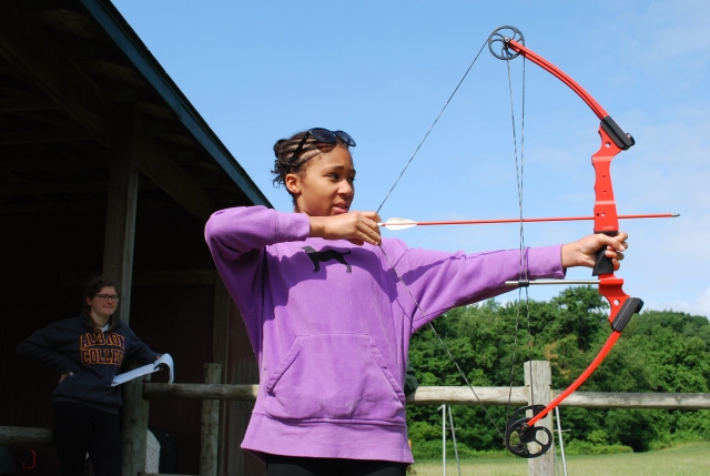  Chica en suéter morado practicando jalo con arco