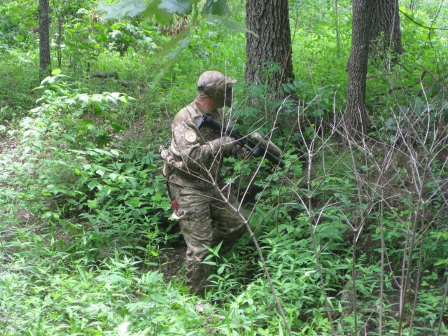  Jugador de gotcha con traje de camuflaje jugando en el bosque 