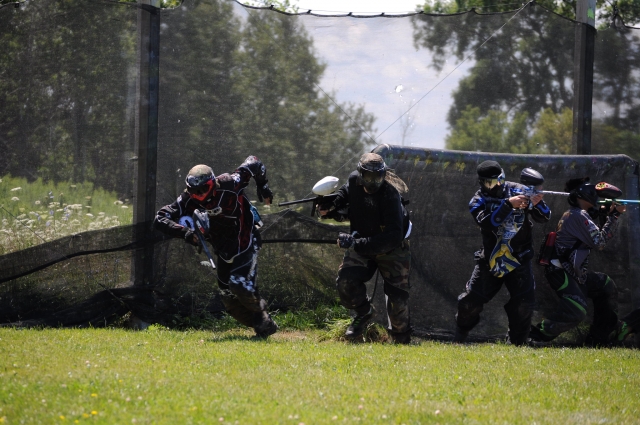 Grupo de amigos con trajes protectores negros jugando gotcha 