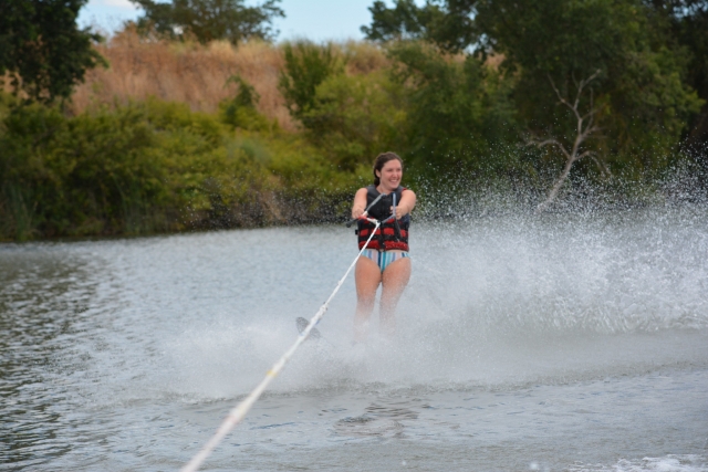 Niña sonrienle y con traje de baño azul y negro haciendo esquí acuático con nosotros