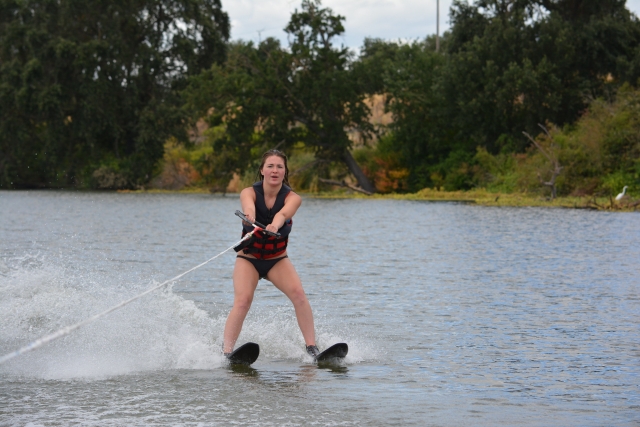 Niña en traje de neopreno negro practicando esquí acuático