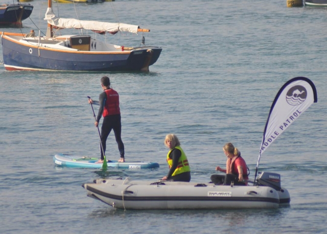 Hombre de paddleboarding en rojo ayudas a la flotabilidad y traje de neopreno negro