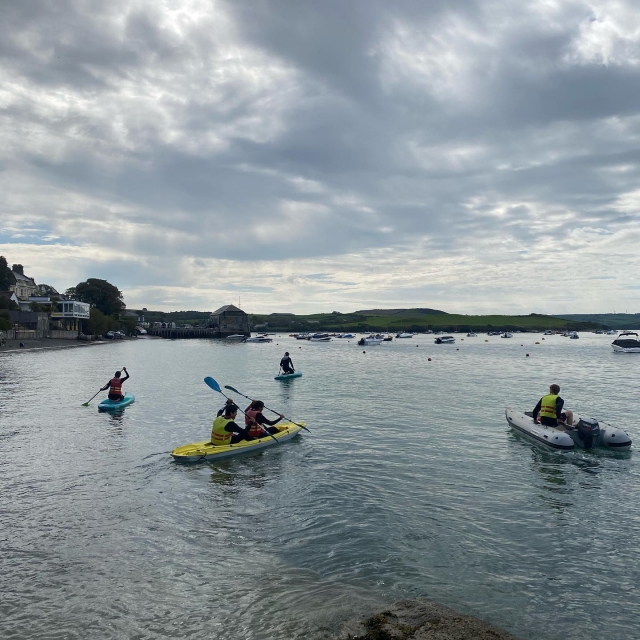 Una pareja en un kayak amarillo cerca de la genle haciendo paddleboard
