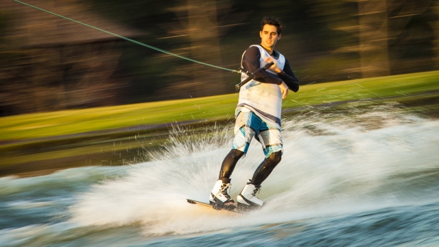 Niño en traje de baño blanco practicando wakeboard