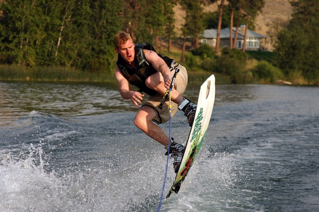Hombre en negro ayudas a la flotabilidad haciendo wakeboard