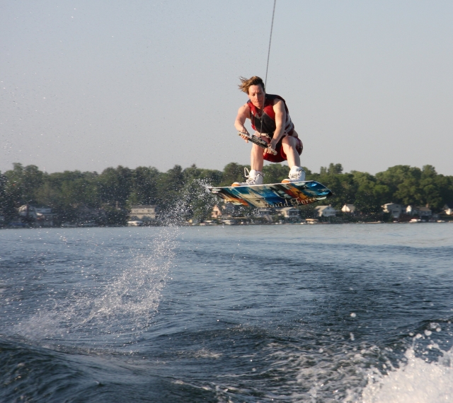 Hombre en rojo ayudas a la flotabilidad volando mientras practica wakeboard