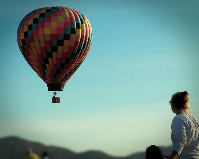 Globo colorido volando sobre el cielo y niña mirando 