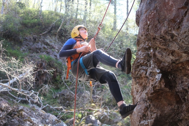 Niño escalando con casco amarillo y chalecos salvavidas naranjas 