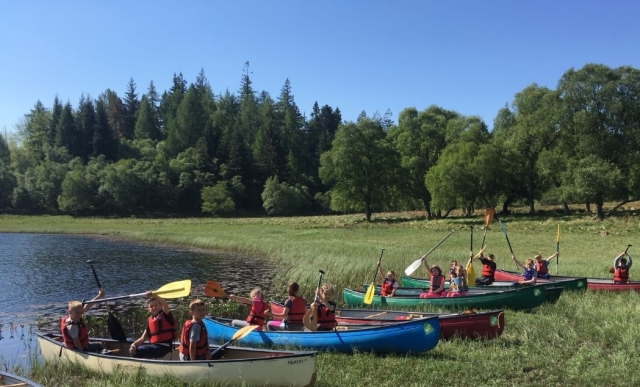  Diferentes niños navegando en canoa con sus remos amarillos y vistiendo boyas rojas, verdes y azules sida 