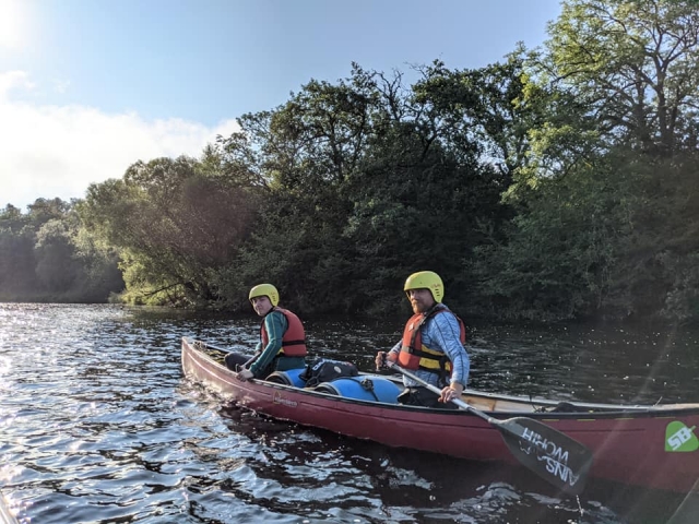 Hombre y mujer con casco amarillo y chalecos rojos en kayak 