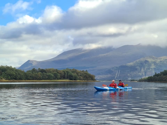 Dos hombres navegando en kayaks azules y con ayudas a la flotabilidad rojas