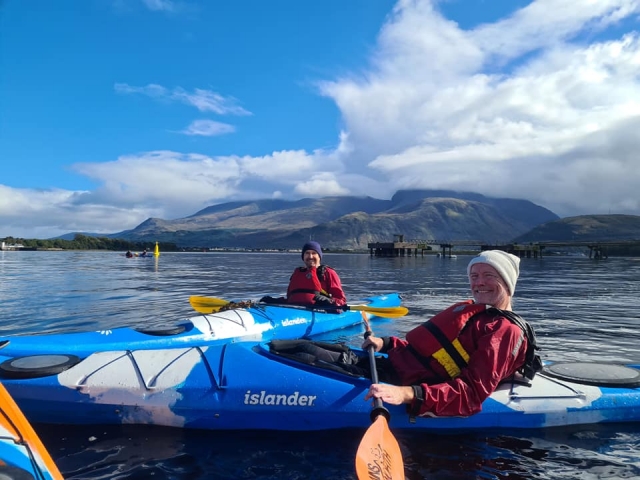 Dos hombres sonriendo vestidos de rojo ayudas a la flotabilidad duranle su sesión de kayak