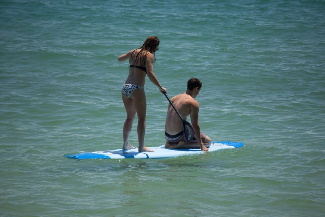 Pareja divirtiéndose remando en una tabla de remo azul