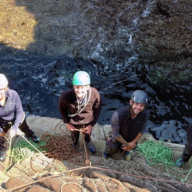 Niños y niñas con cascos negros sonriendo y a punto de escalar