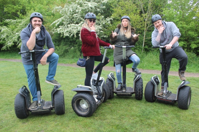  A unas niñas y dos niños con cascos grises y posa antes de dar una vuelta en segway por el parque