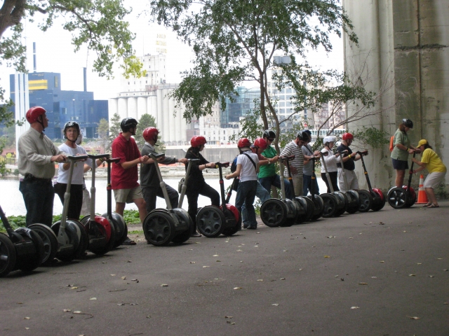  Personas usando cascos rojos y negros preparándose para comenzar su aventura en segway