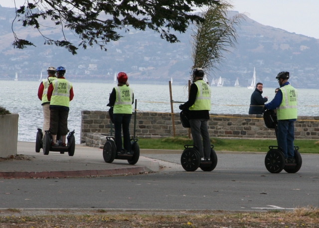  Cuatro personas con cascos negros haciendo segway por el parque 