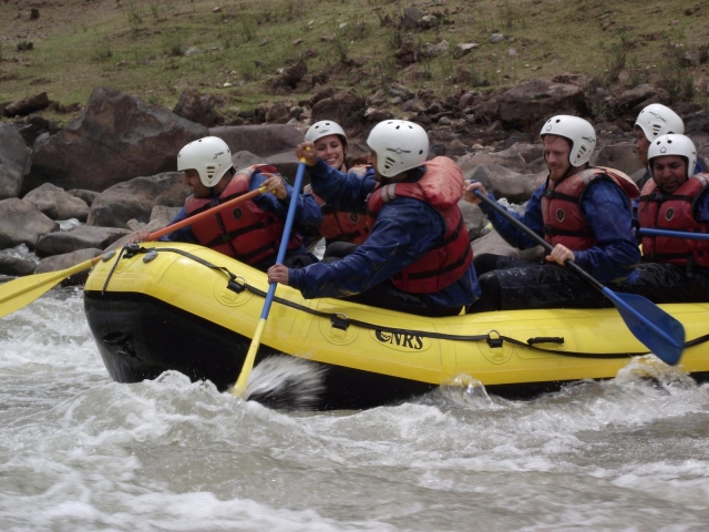  Personas con cascos blancos, chalecos salvavidas rojos y trajes de neopreno azules, rafting 