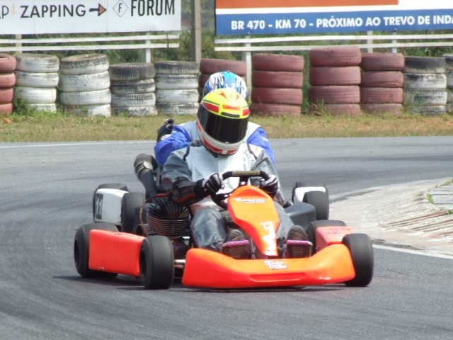 Alguien con casco amarillo y manejando un kart naranja