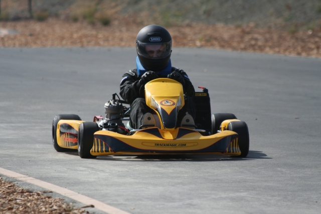 Hombre con traje de conducción negro manejando kart amarillo