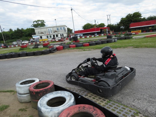 Hombre con traje de manejar negro practicando karting