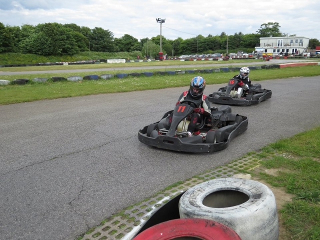 Dos amigos con traje de conducción negro practicando karting