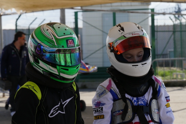  Niño y niña con equipamiento verde y blanco preparándose antes del karting