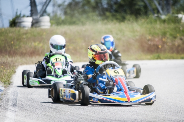  Personas vestidas con trajes de conducción verdes y azules practicando karting