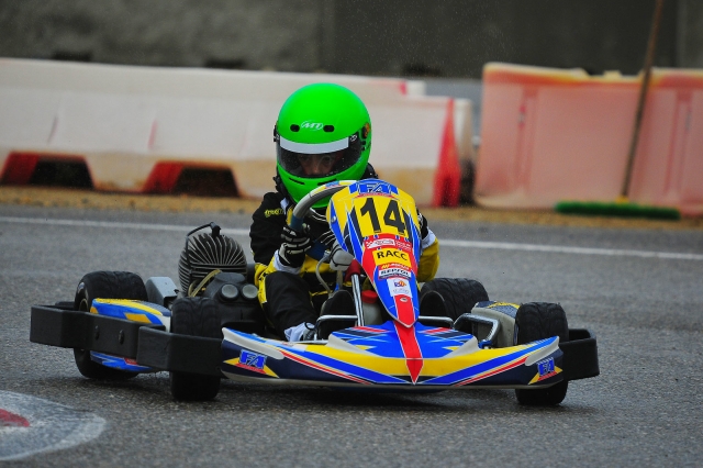  Niño con casco verde y manejando karting azul