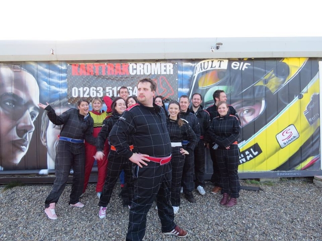 Grupos de amigos vestidos con monos de conducción negros preparándose para la carrera